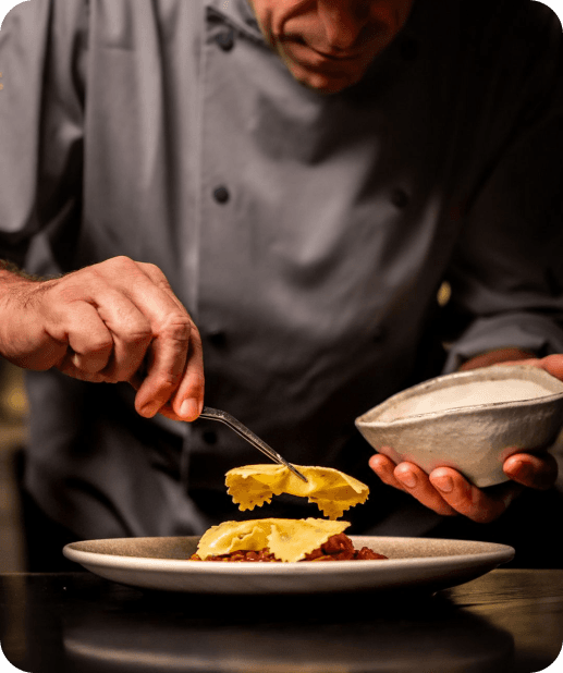 Chef plating ravioli in a restaurant kitchen